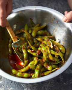 Tossing Spicy edamame in a bowl